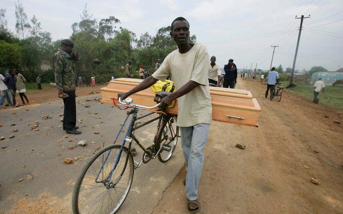 KISUMU - Een man loopt met een doodskist achter op zijn fiets langs een controlepost van de politie in de stad Kisumu. De meeste mensen van de Kikuyustam hebben de stad inmiddels verlaten. Velen spreken over een etnische zuivering van het land. Vrijdagavo