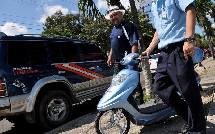 HAVANA - Gliberto Guerra (r) verlaat een winkel in Havana met zijn nieuwe aankoop: een scooter van 994,40 convertibele peso's, een munteenheid die wordt gehanteerd voor toeristen en die 24 maal de waarde heeft van de peso waarin Cubaanse werknemers worden