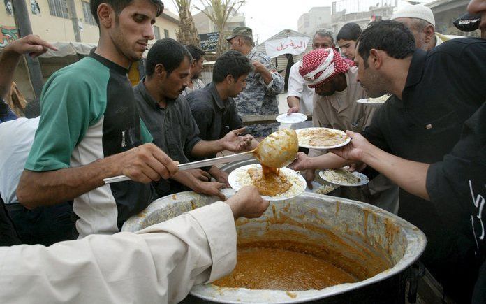 Irakezen ontvangen voedsel in een sjiitische wijk van Bagdad. Ondanks de enorme olie inkomsten zijn duizenden Irakezen nog elke dag van voedselhulp afhankelijk. Foto EPA