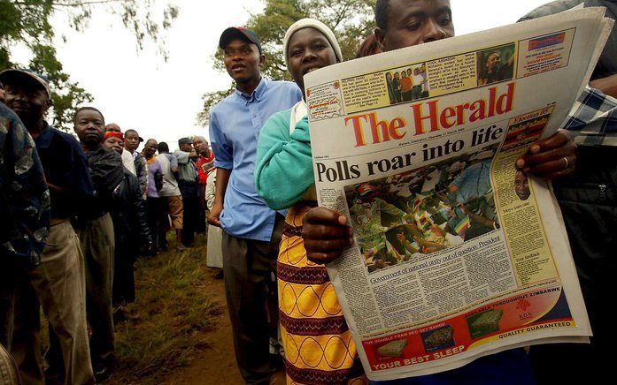 Een man leest een buitenlandse krant voor het stemlokaal in Zimbabwe, vorige week. Foto EPA