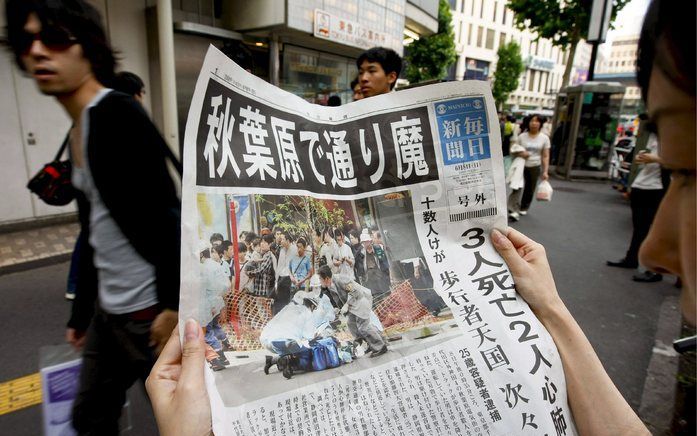 TOKIO - Een vrouw leest de krant nadat Tomohiro Kato een bloedbad aanrichtte in Akihabara, een winkelcentrum in een ander deel van de hoofdstad. In Japan zijn vier mensen gearresteerd die op websites hebben gedreigd een voorbeeld te nemen aan Kato. Foto E