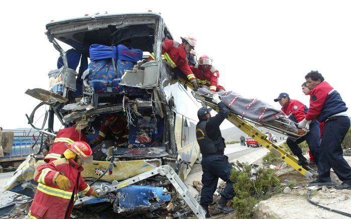 Reddingswerkers bergen lichamen uit het wrak van de verongelukte bus. Foto EPA