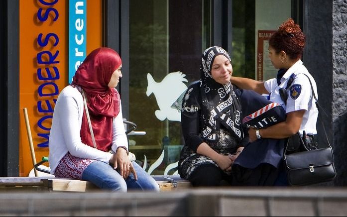 Een politieagent troost dinsdag een vrouw bij het kinderdagverblijf Moeders Schoot in Amsterdam. Foto ANP