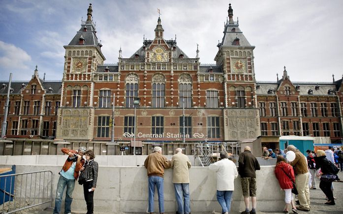 AMSTERDAM - Bezoekers bekijken de bouwplaats voor de Noord/Zuidlijn op het Damrak voor het Centraal Station in Amsterdam. Foto ANP