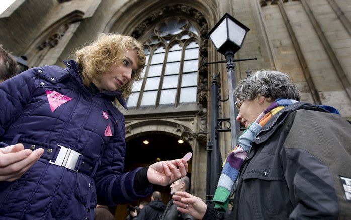 DEN BOSCH – Een actievoerder deelde zondag een roze hostie uit aan een kerkganger voor de Sint-Jan in Den Bosch. De eucharistieviering verliep door protesten van homoseksuelen en sympathisanten zeer onrustig. Foto ANP