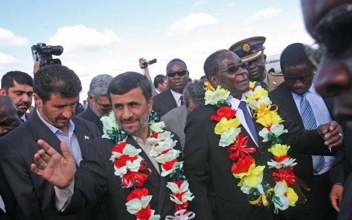 De Iraanse president Ahmadinejad (l.) met zijn Zimbabwaanse collega Mugabe na aankomst op de luchthaven van Harare donderdag.