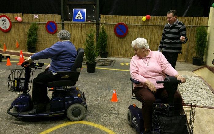 Het slalommen over een kronkelende lijn, tussen pionnen door, vormt een onderdeel van de scootmobielcursus van Mobiel Centrum Nederland. De oefening vereist stuurmanskunst. „Blijf bij het achteruitrijden beurtelings over beide schouders kijken”, adviseert