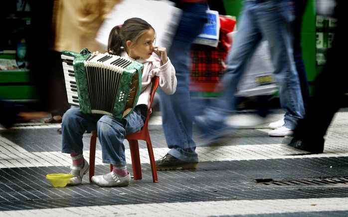 Een meisje probeert in het centrum van Buenos Aires geld te verdienen als straatmuzikantje. Leerlingen van basisschool L. W. Beekman in Den Bosch protesteerden dinsdag tegen kinderarbeid door musicerende leeftijdsgenootjes in hun stad. Foto ANP