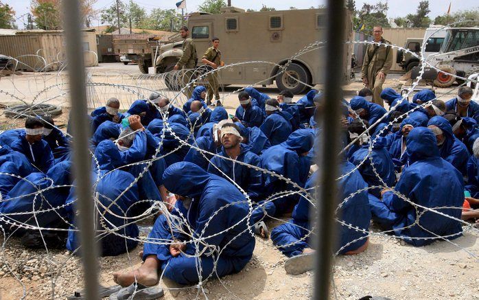 JERUZALEM - Geblinddoekte Palestijnse gevangenen wachten op een militaire basis in de Gaza strook. Foto EPA