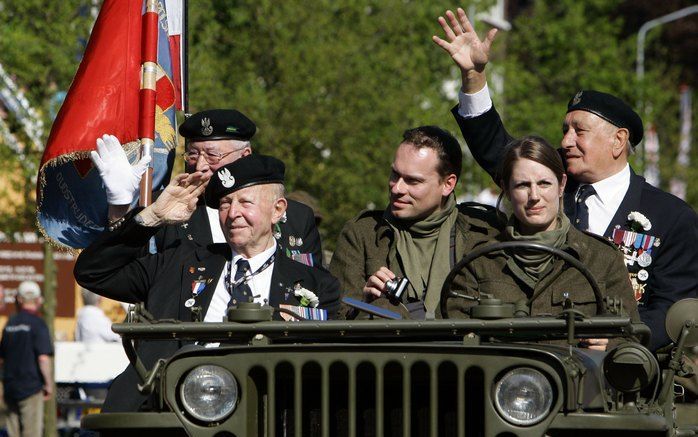 WAGENINGEN - Veteranen zwaaien vanuit historische militaire voertuigen tijdens de derde editie van het Vrijheidsdefile maandagmiddag. De route van het defile passeert ondermeer voorbij aan Hotel De Wereld, de plaats waar de Duitse capitulatie op 5 mei 194