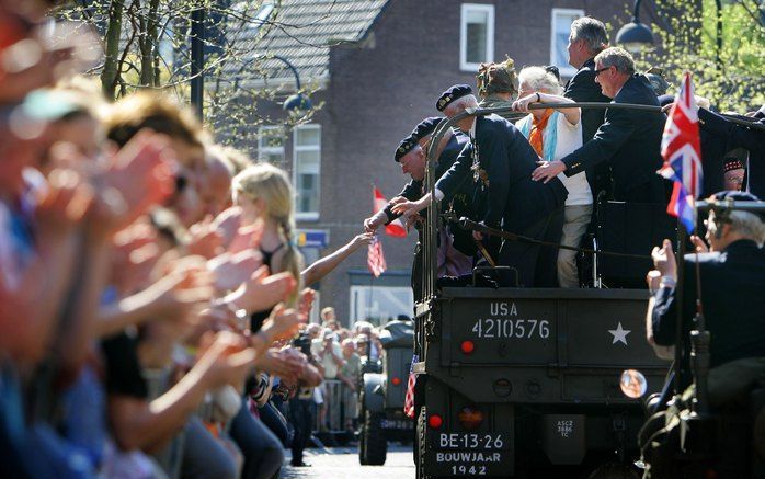 WAGENINGEN - Veteranen zwaaien vanuit historische militaire voertuigen tijdens de derde editie van het Vrijheidsdefile maandagmiddag. De route van het defile passeert ondermeer voorbij aan Hotel De Wereld, de plaats waar de Duitse capitulatie op 5 mei 194