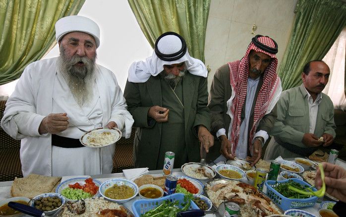 De geestelijk leider van de Yezidi’s, Baba Sheikh (l.), nuttigt met enkele geloofsgenoten de maaltijd. Foto: Anton Dommerholt