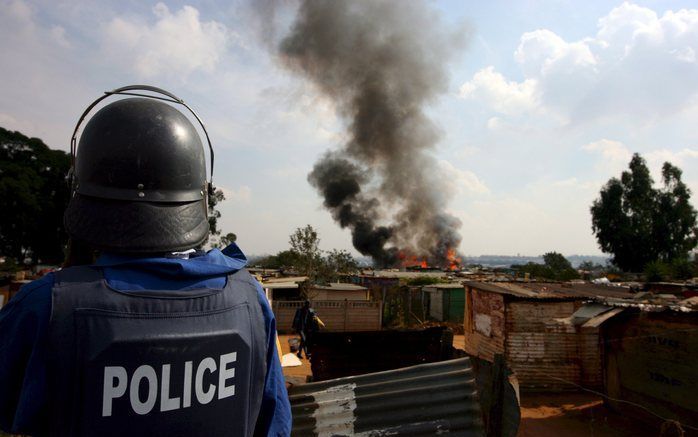 Een politieman kijkt toe hoe vuur woningen verwoest in Johannesburg. Foto's EPA