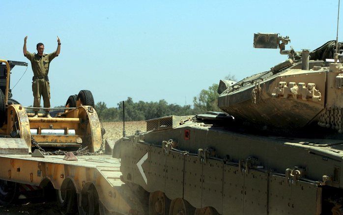 ISRAEL - Een soldaat geeft aanwijzingen aan zijn collega voor het oprijden van een tank in de Gaza-strook. Foto EPA