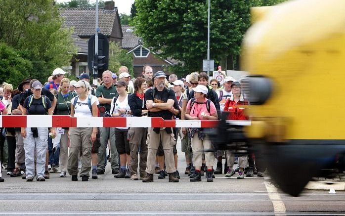 WIJCHEN - Wandelaars aan de 93 editie van de Nijmeegse Vierdaagse moetn wachten voor een gesloten spoorwegovergang bij het passeren door het centrum van Wijchen woensdagmiddag. De Internationale Vierdaagse Afstandsmarsen Nijmegen is werelds grootste wande