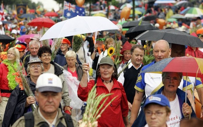 NIJMEGEN - Wandelaars aan de 92e editie van de Nijmeegse Vierdaagse komen in de stromende regen onder een woud van paraplu's binnen op de Via Gladiola vrijdagmiddag. Foto ANP