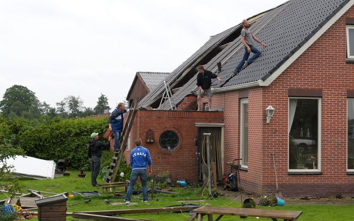 LUTJEGAST – Bewoners van een Groningse woning leggen op het dak van het woongedeelte de afgewaaide dakpannen terug. Het dakdeel van de stal werd in zijn geheel weggeblazen. Een windhoos zorgde zondagavond voor veel schade in de Groningse dorpen Lutjegast,