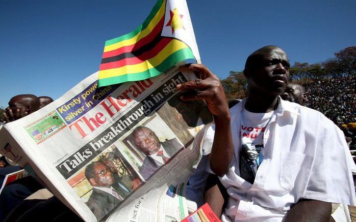 Een Zimbabwaan verkoopt kranten waarin op de voorpagina melding wordt gemaakt van het overleg tussen Mugabe en Tsvangirai. Foto EPA