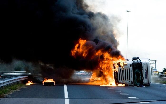 BAARN - Een vrachtwagen op zijn kant staat maandag in lichterlaaie op de A1 bij Baarn. Het ongeluk gebeurde vermoedelijk nadat de chauffeur onwel was geworden en zijn truck de linkervangrail raakte. Foto ANP