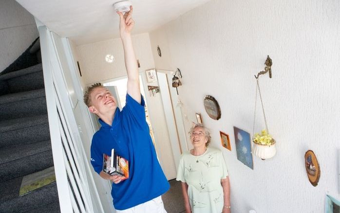 WESTLAND - Een leerling bevestigt een gratis rookmelder bij een huurder van Vestia Westland. Foto ANP