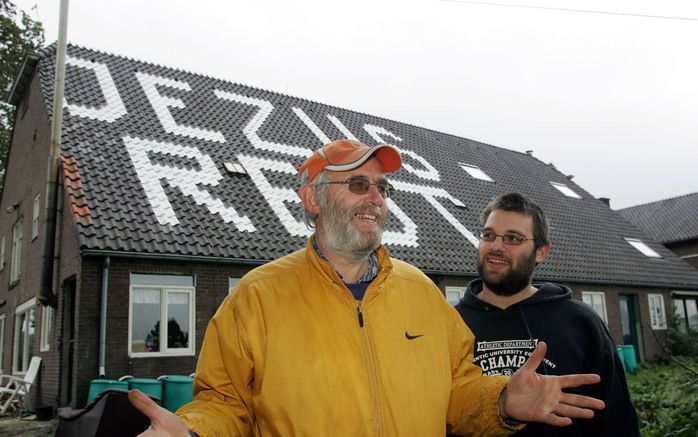 GIESSENBURG – Joop van Ooijen met zijn zoon Moshe voor de familieboerderij in Giessenburg. De tekst ”Jezus redt” die het dak siert, moet van de gemeente Giessenlanden voor 4 november verdwenen zijn. Foto Rein Geleijnse