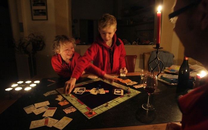 Tijdens de stroomstoring doen mensen een spelletje bij kaarslicht. Foto ANP