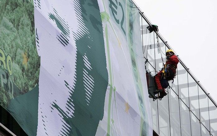 DEN HAAG - Actievoerders van Greenpeace hangen woensdagochtend een bankbiljet aan de gevel van het ministerie van Financiën. Foto ANP