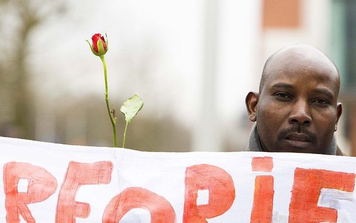 Een Sudanees houdt een roos en een spandoek omhoog tijdens een demonstratie van enkele tientallen mensen voor het gebouw van het Internationaal Strafhof in Den Haag. Ze wilden de slachtoffers in de Sudanese regio Darfur gedenken. Het strafhof vaardigde wo