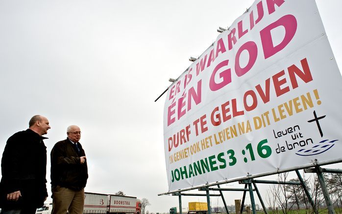 STAPHORST – Sinds vorige week donderdag kunnen automobilisten op de A28 bij Staphorst de tekst ”Er is waarlijk één God” lezen. De gereformeerde predikant M. J. Heule (rechts) besloot vorige week het bord te plaatsen. Enkele gemeenteleden, waaronder H. Bis