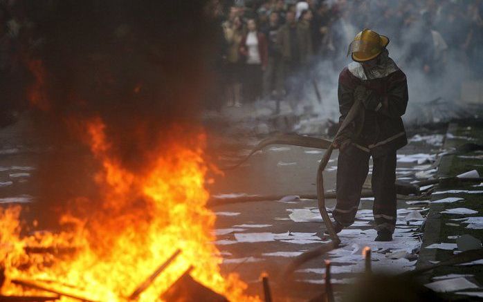 CHISNAU - Een Moldavische brandweerman blust een vuurtje voor het parlementsgebouw. Foto EPA