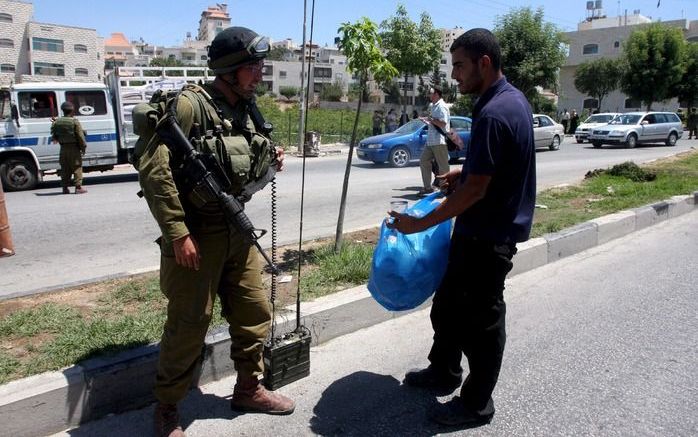 Een Israëlische soldaat controleert een Palestijn in Hebron op de Westoever. Foto: EPA