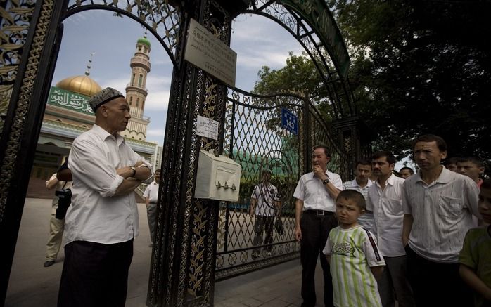 Oejgoeren staan vrijdag voor een gesloten moskee in Urumqi. De meeste moskeeën bleven gesloten in verband met de onveilige situatie. Foto EPA