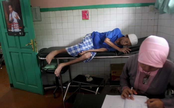 JAKARTA – Een Indonesische aidspatiënt verlaat de behandeltafel, terwijl een verpleegkundige zijn medisch dossier bijwerkt. De strijd tegen aids verloopt moeizaam in Indonesië. Pas in 2005 ondernam de regering serieuze actie. Het officiële aantal patiënte