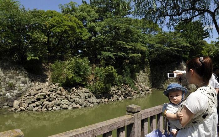 TOKIO - Een Japanse vrouw maakt een foto van een dam die door de beving instortte. Foto EPA