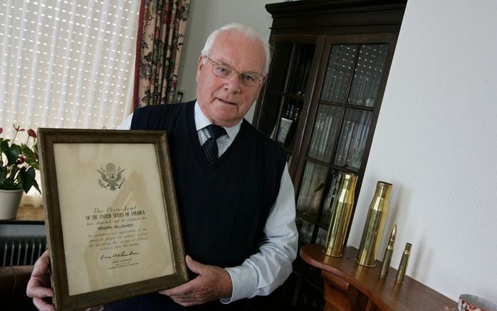 Opheusdenaar J. H. Willemsen met de oorkonde die zijn vader ontving voor het verbergen van een Amerikaanse piloot. Rechts van hem patroonhulzen uit 1944 die hij op de schoorsteenmantel heeft staan. Foto RD, Anton Dommerholt