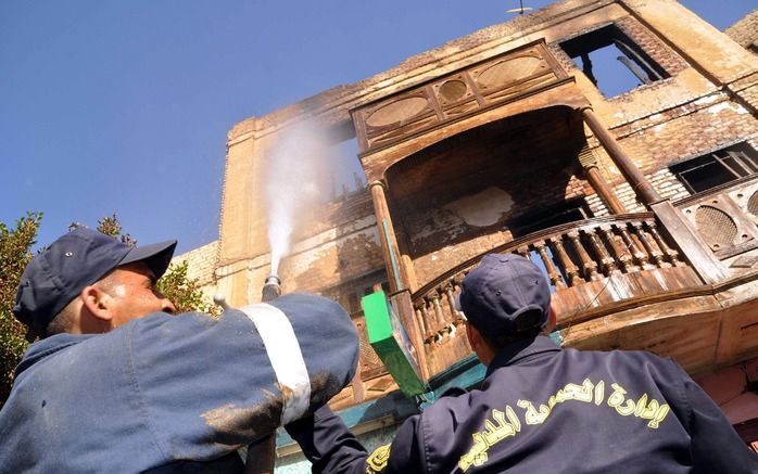 Brandweermensen blussen het huis van Koptische christenen in Zuid-Egypte. - Foto EPA