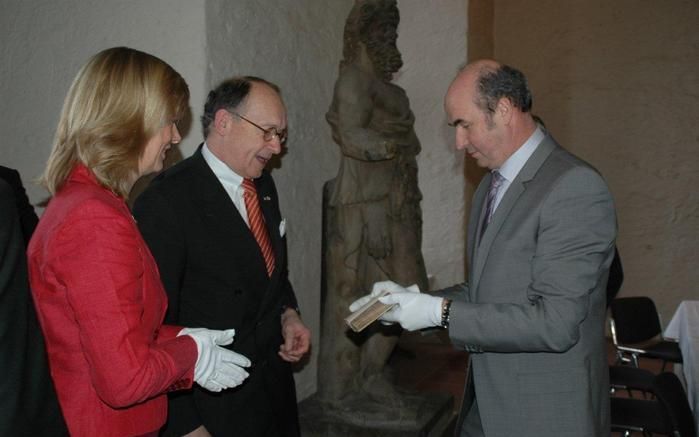 HEIDELBERG – Prof. dr. F. Hepp (r.) van het Kurpfälzisches Museum in Heidelberg, toont een eerste druk van de Heidelbergse Catechismus aan burgemeester G. J. de Graaf van Apeldoorn en Karla Apperloo van Refo500. Zij halen in het kroonjaar 2013 de catechis