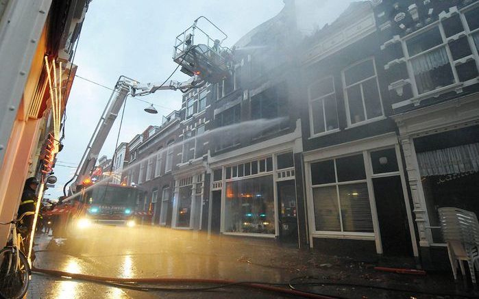 DORDRECHT – Medewerkers van de brandweer blussen een uitslaande brand in de Voorstraat te Dordrecht. In de vlammenzee raakten vijf personen gewond. Een vrouw sprong vanaf de eerste verdieping door het raam om zichzelf in veiligheid te brengen. Zij kwam er