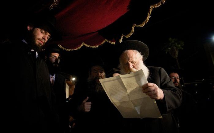 Bruiloft in orthodox Israël. Met gesloten ogen luistert de bruidegom (l.) naar het voorlezen van de huwelijksakte. Foto Sjaak Verboom