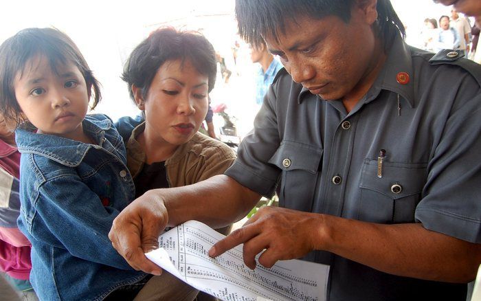 JAKARTA - Familieleden bekijken de passagierslijst van de zondag gezonken veerboot. Foto EPA