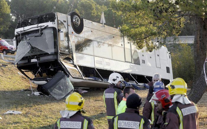 Brandweermannen maandagochtend bij de bus die op de A7 bij de Spaanse stad Gerona kantelde. Foto ANP