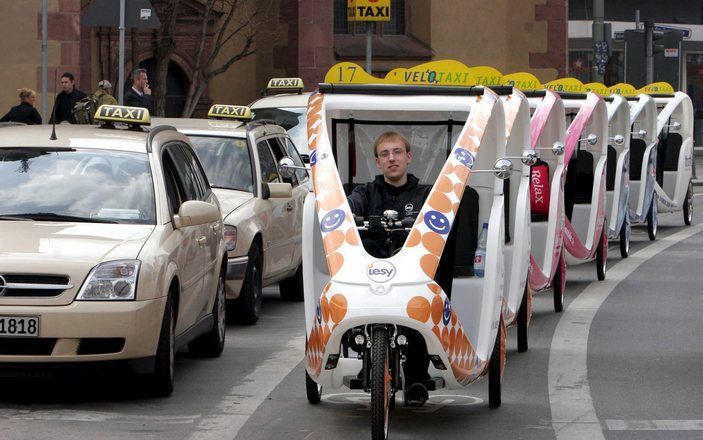 GOUDA – Gouwenaars zijn enthousiast over de velotaxi, een fietstaxi met een elektrische hulpmotor. Het milieuvriendelijke voertuig reed in december op proef door de Goudse binnenstad. Foto: een rij velotaxi’s in de Duitse stad Frankfurt. Foto EPA