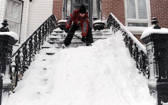 Een vrouw maakt de trap voor haar huis sneeuwvrij in Brooklyn, New York. Foto EPA