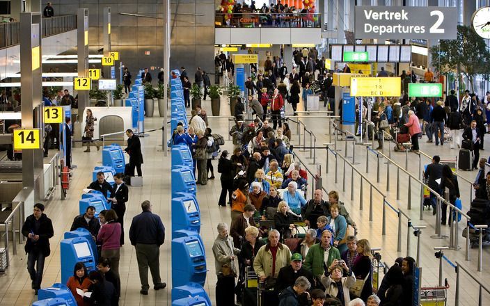 Mensen staan in de rij om in te checken op Schiphol. Foto ANP