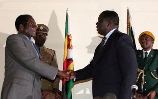 President Mugabe (links) en oppositieleider Tsvangirai schudden elkaar de hand nadat ze eerder deze week een overeenkomst sloten om met elkaar in gesprek te gaan. Foto EPA