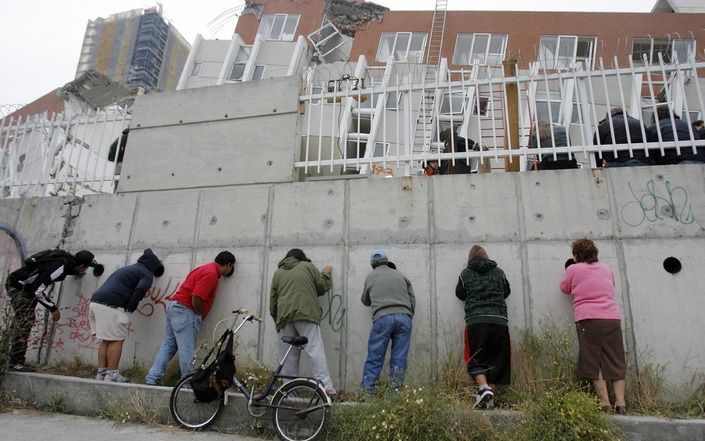 Bewoners van een appartementencomplex kijken naar de beschadiging van hun woningen. Foto EPA