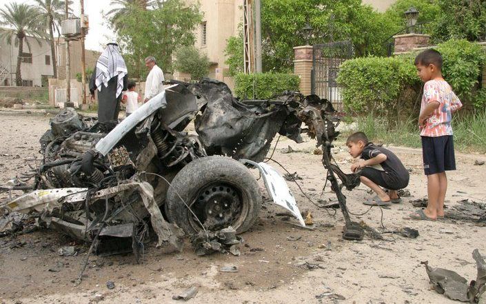 BAGDAD – Twee jeugdige Irakezen inspecteren in de hoofdstad Bagdad een wrak van een opgeblazen auto. Tientallen Irakezen kwamen de afgelopen dagen om het leven bij een opleving van het religieuze geweld in het Tweestromenland. Foto EPA