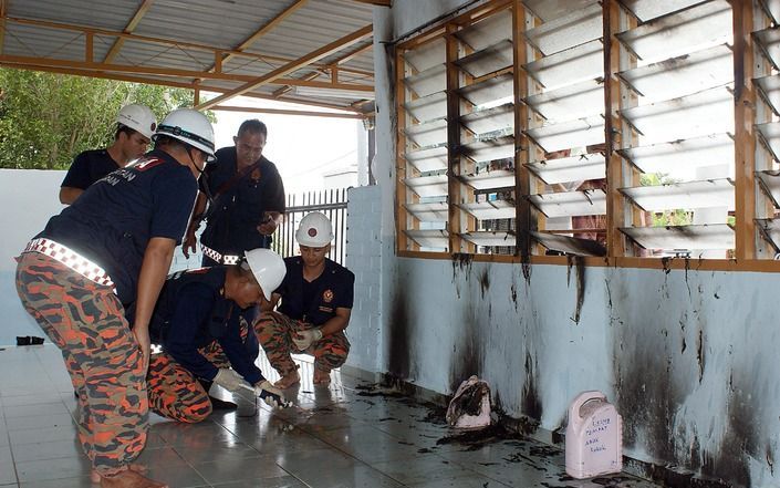 Politiemensen bekijken de schade die ontstaan is aan een moskee in Muar. Foto EPA