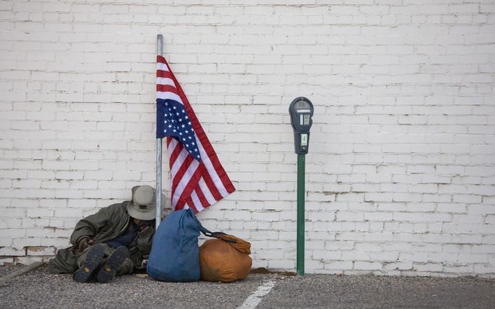 Zwerver op straat in Colorado met omgekeerd geknoopte vlag, een roep om hulp. Foto ANP