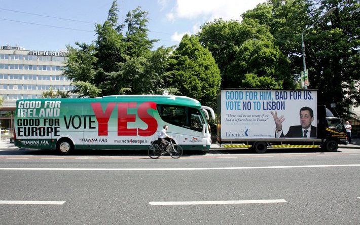 DUBLIN - Een fietser in de Ierse hoofdstad Dublin passeert twee bussen die zowel oproepen 'JA' als ´NEE´ te zeggen tegen het Europese referendum, dat vandaag in Ierland wordt gehouden. - Foto EPA